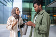 © Jovo Jovanovic/Stocksy - Two young professionals discuss work outside an office building.