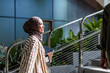 © Jovo Jovanovic/Stocksy - Smiling woman in hijab walks with tablet and ID.