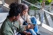© Jovo Jovanovic/Stocksy - Students collaborate on a tablet while sitting on stairs.
