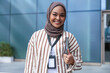 © Jovo Jovanovic/Stocksy - Smiling woman in hijab with ID badge and tablet.