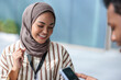© Jovo Jovanovic/Stocksy - Smiling woman in hijab looks at phone with stylus.
