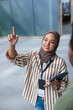 © Jovo Jovanovic/Stocksy - Woman in hijab points upward, holding tablet, giving tour.