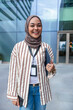 © Jovo Jovanovic/Stocksy - Smiling woman in hijab with ID badge and tablet.