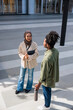© Jovo Jovanovic/Stocksy - Two young professionals converse outdoors in a modern setting.