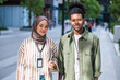 © Jovo Jovanovic/Stocksy - Two young professionals smiling outdoors with ID badges.