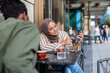 © Jovo Jovanovic/Stocksy - Woman in hijab shows phone to friend at cafe.