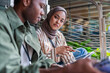 © Jovo Jovanovic/Stocksy - Two young adults working together on tablets outdoors.