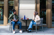© Jovo Jovanovic/Stocksy - Young couple conversing over coffee at an outdoor cafe.