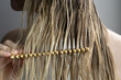 © Asya Molochkova/Stocksy - Woman Combing Hair with Wooden Comb Closeup