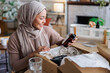 © Jovo Jovanovic/Stocksy - Influencer in hijab unboxing beauty products
