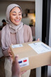 © Jovo Jovanovic/Stocksy - Muslim woman happy to receive package