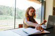 © BONNINSTUDIO/Stocksy - Woman using laptop and notebook at modern office