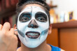 © NAILOTL MENDEZ/Stocksy - Boy getting skull makeup for dia de muertos