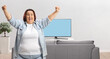 © Ljupco Smokovski - Excited plus-size woman cheering in front of TV