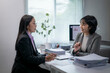 © Wasana - Two businesswomen discussing business strategy in office meeting