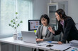© Wasana - Two businesswomen are discussing over project using laptop in the office