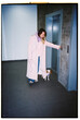© Asya Molochkova/Stocksy - Film photo of woman with small dog waiting for elevator