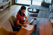 © Artcore Studio/Stocksy - Woman working remotely from home signing documents on table