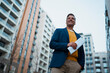 © Artcore Studio/Stocksy - Smiling man holding documents looking at city buildings
