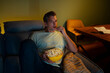 © Artcore Studio/Stocksy - Man relaxing on couch watching tv eating popcorn