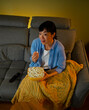 © Artcore Studio/Stocksy - Woman enjoying evening movie night while eating popcorn