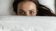 © fizkes - Night time fear. Close up top view portrait stressed scared young lady lying on bed suddenly awakened from nightmare peek from duvet with wide terrified eyes afraid of darkness feel vulnerable unsafe