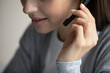 © fizkes - Digital audio communication. Close up cropped shot face young woman wear comfortable headset touch microphone when speaking. Tech support line virtual meeting customer service hotline operator concept