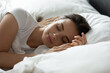 © fizkes - Peaceful night rest. Tired young woman sleep on side in early morning in soft bed with orthopedic mattress breathing deep lying with closed eyes on supportive memory foam pillow under cozy warm duvet