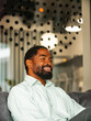 © Aleksandra Jankovic/Stocksy - Smiling Man in Light Green Shirt Sits in Modern Office Lounge