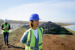 © Artcore Studio/Stocksy - Woman in safety gear observes solar panel installation site