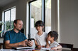 © NZstockphoto - A father shows something on a mobile phone to his two curious children while at home