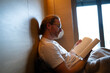 © Artcore Studio/Stocksy - Man reading a book in a cozy bedroom on a quiet morning