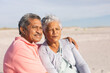 © wavebreak3 - Thoughtful multiracial senior couple looking away while relaxing at beach on sunny day