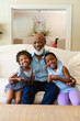 © wavebreak3 - African american grandfather and two granddaughters with digital tablet smiling at home