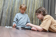 © Victor zastol'skiy - Two boys playing a strategic board game at a wooden table. Children focused on a game