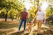 © Jelena - Joyful family stroll in a vibrant park during golden hour