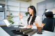 © Stella 16 - Asian woman taking via laptop video call conference remote at office workplace.