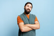 © Maria Vitkovska - Bearded man smiling with arms crossed, standing confident on blue background