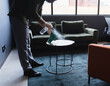 © Wavebreak Media - Man wearing gloves cleaning side table in office lounge with spray bottle and cloth, copy space