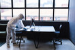 © Wavebreak Media - Mid-adult man wearing coverall disinfecting desk with spray bottle and cloth at office, copy space