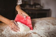 © Wavebreak Media - Middle-aged Asian woman in apron kneading and shaping dough with red scraper on bakery counter