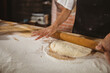 © Wavebreak Media - Asian woman wearing black apron rolling dough with rolling pin on floured countertop at bakery