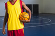 © Wavebreak Media - Mid adult African-American athlete holding ball on gym court wearing basketball jersey, copy space