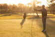 © Wavebreak Media - African American man gripping flagstick on putting green with golf bag near pond, copy space