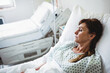 © Wavebreak Media - Senior woman lying on hospital bed in gown with pillow-blanket beside bed IV pole, copy space