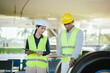 © Natthawadee - Two engineers in safety helmets and reflective vests inspect an aircraft landing gear tire while reviewing maintenance data on digital tablets at an airport maintenance area.