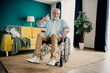 © deagreez - Elderly man in wheelchair in a bright living room giving a thumbs up, a warm home scene promoting inclusion, disability awareness, family comfort, and positive hope