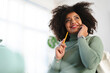 © Studio Marmellata - A woman with curly hair smiles while holding a pencil and talking on her phone, looking up thoughtfully.
