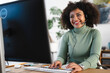 © Studio Marmellata - A smiling woman wearing a headset works at her computer, typing on the keyboard and looking at the screen.