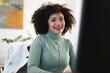 © Studio Marmellata - A smiling woman with curly hair wears a headset and a green turtleneck while working at her desk.